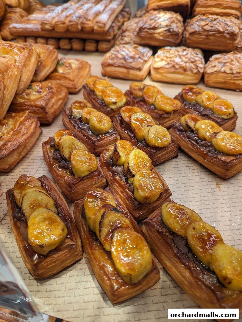 A close-up view of various freshly baked pastries, including banana tarts and almond croissants.
