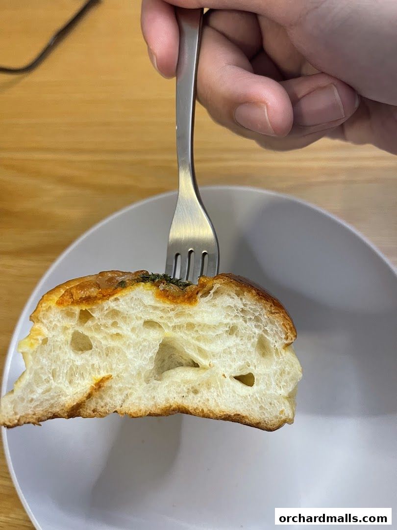 A fork is piercing a slice of fluffy bread with a golden-brown crust.