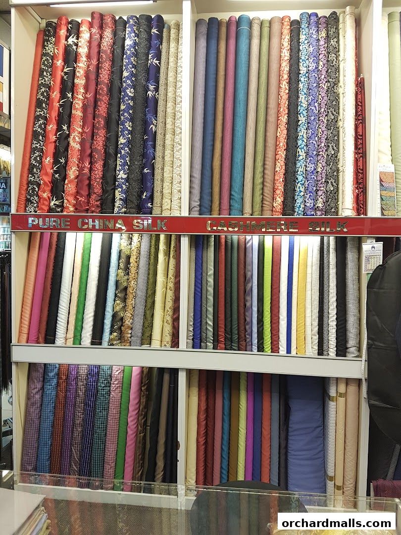A wide selection of colorful fabrics, including silk and cashmere, neatly rolled and displayed.