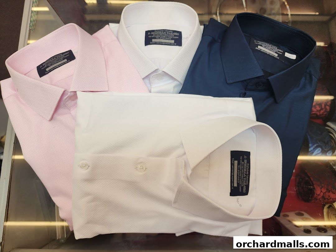 A display of neatly folded dress shirts in pink, white, and navy blue.