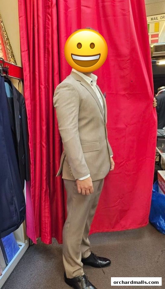 A person models a tailored suit in front of a red curtain at Le Modella Tailors.