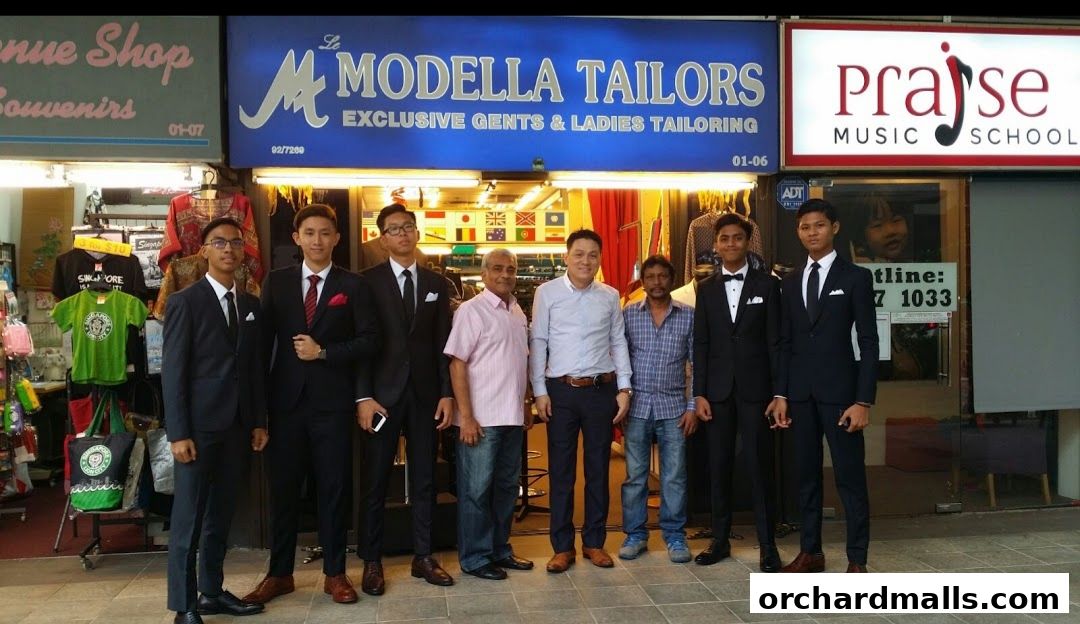 Le Modella Tailors shop front with staff in suits and merchandise displayed.