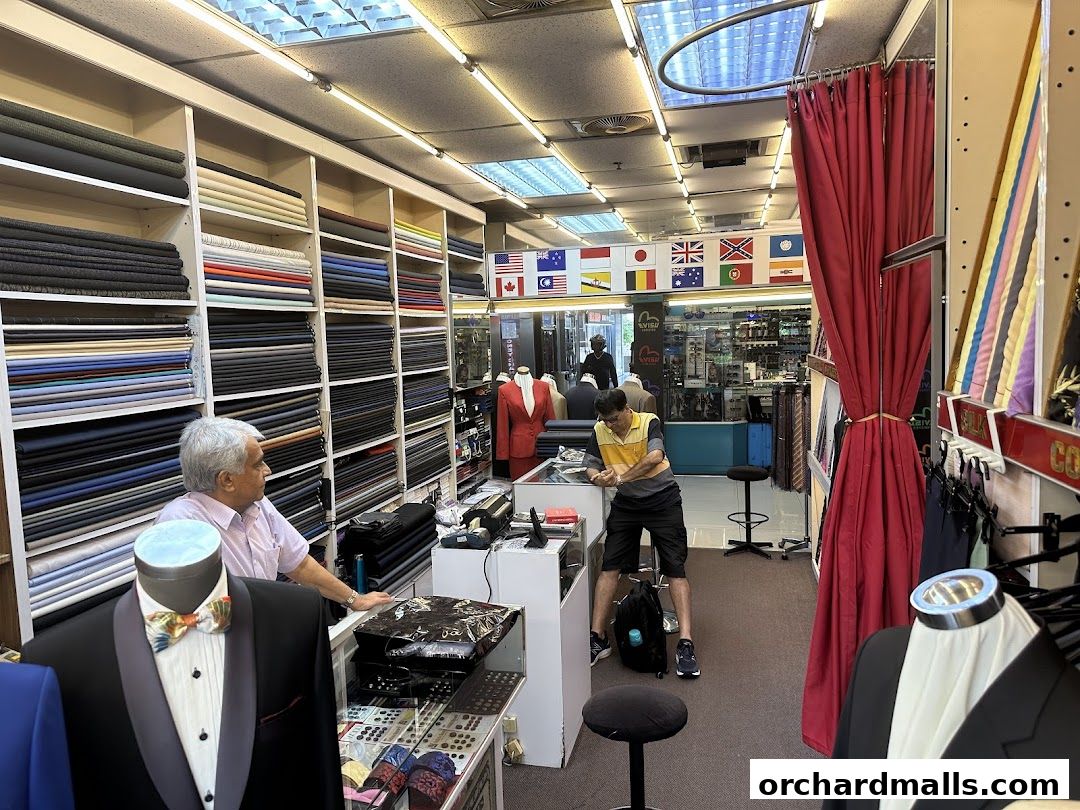 Tailor shop interior with fabric rolls, mannequins, and staff assisting customers.