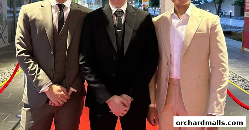 Three men in tailored suits stand on a red carpet, showcasing elegant formal wear.