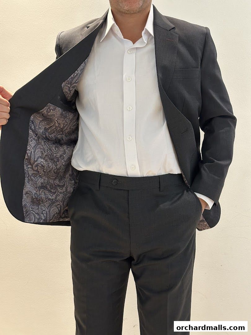 A person wearing a dark grey suit with a white shirt, showing the paisley lining of the jacket.