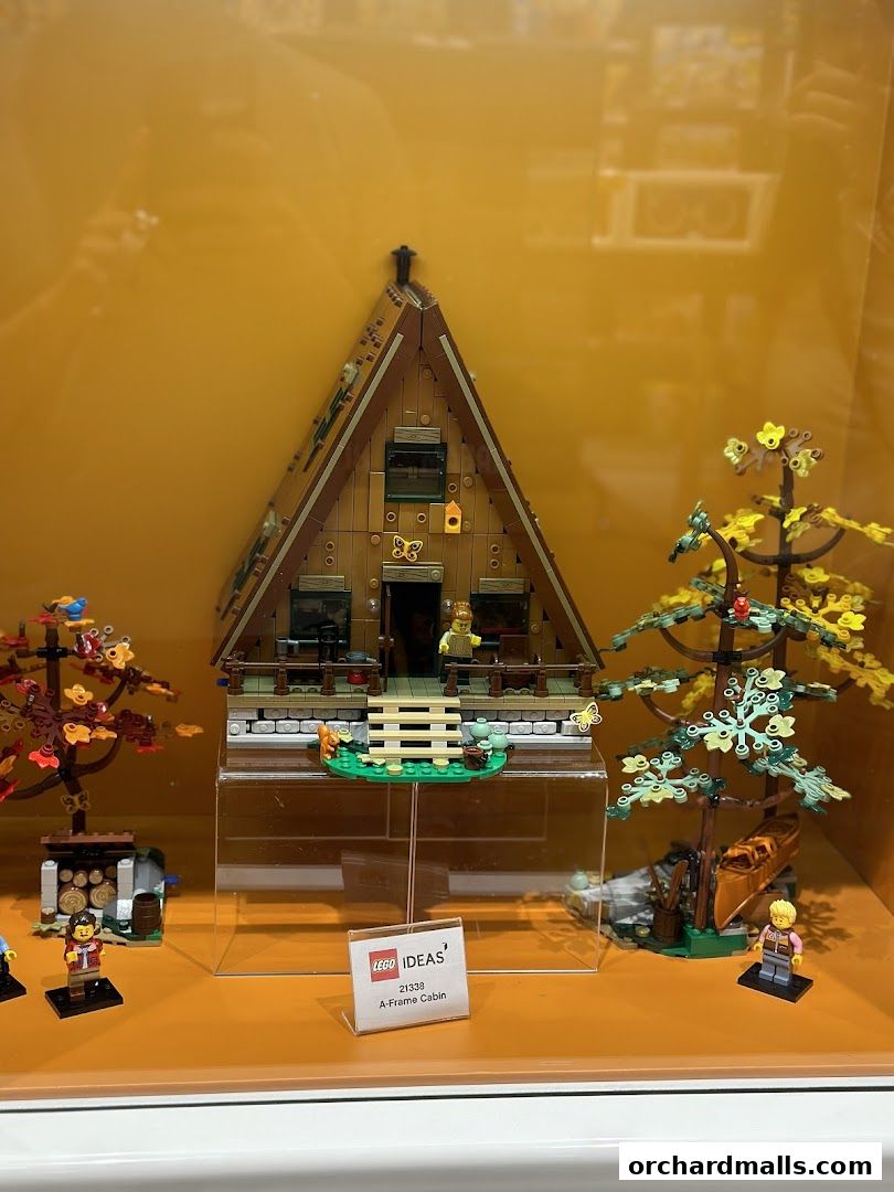 A LEGO A-Frame Cabin set displayed with minifigures and accessories in a store window.