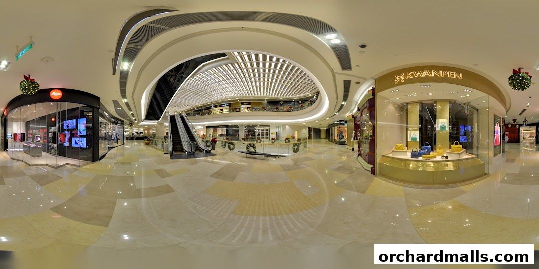 Interior view of a modern shopping mall with various stores and escalators.