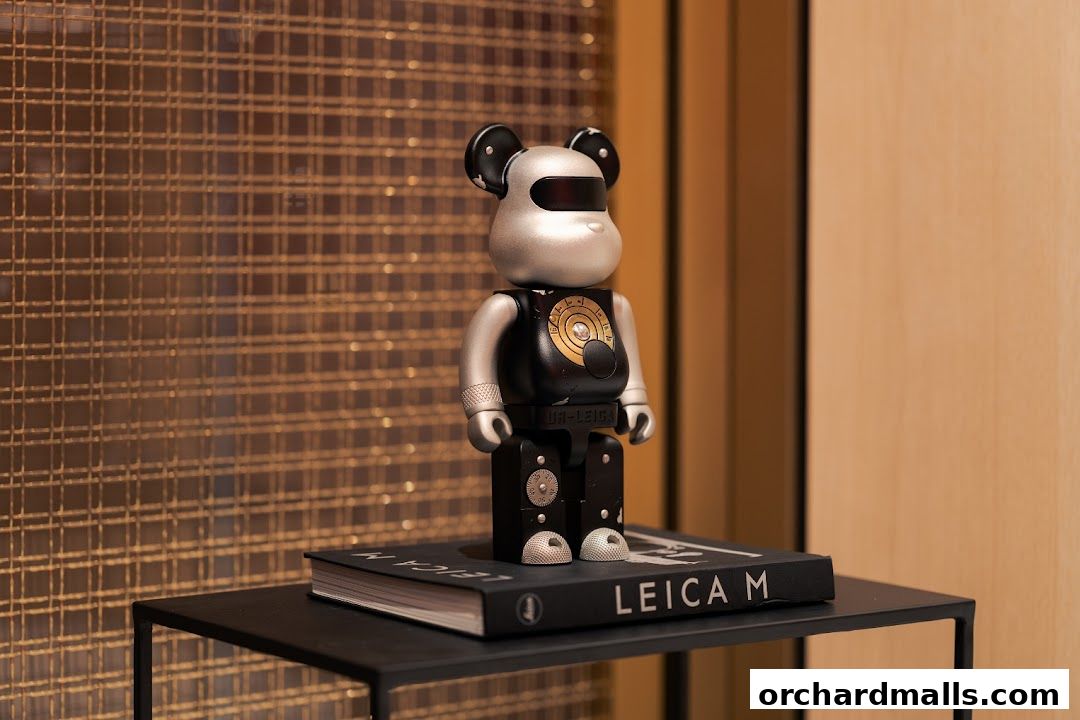 A Leica branded Bearbrick toy sits on a book titled 'LEICA M'.