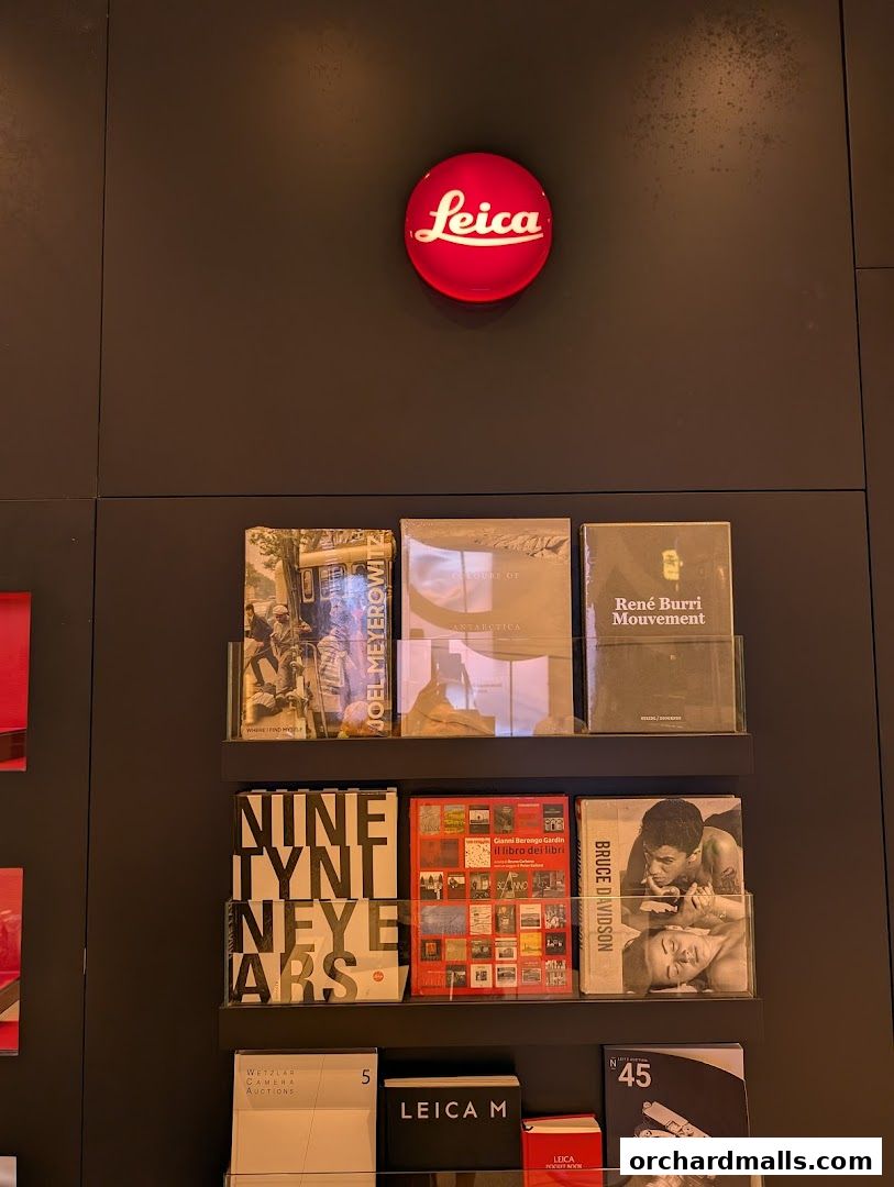 Leica store interior with books and the iconic red Leica logo on the wall.