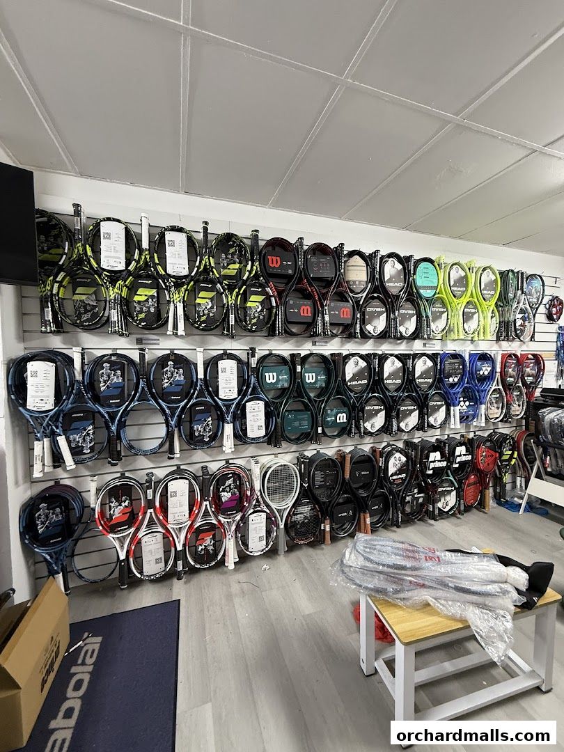 A wide selection of tennis rackets displayed on a wall in a sports shop.