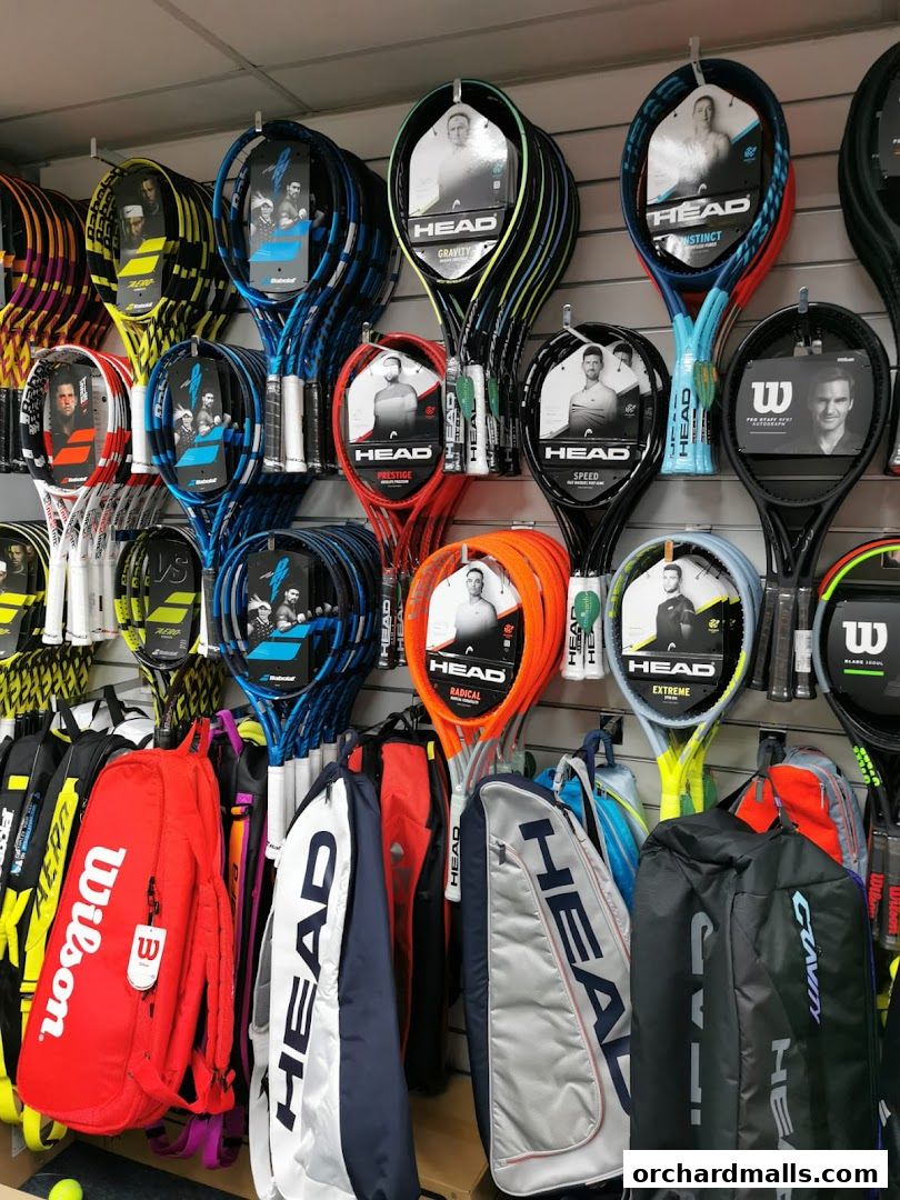 A display of tennis rackets and bags from brands like HEAD and Wilson.