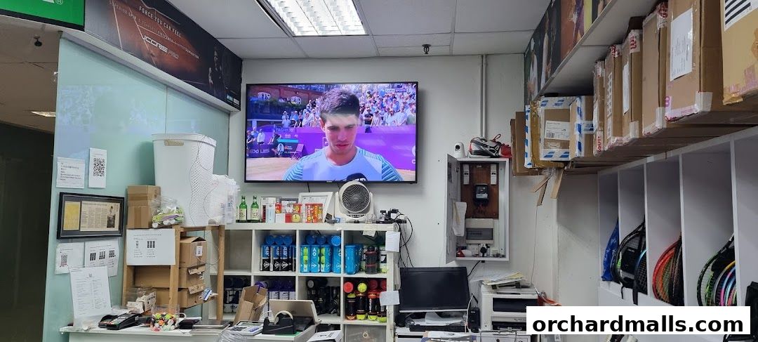 Interior of a sports shop displaying tennis rackets, balls, and other equipment.