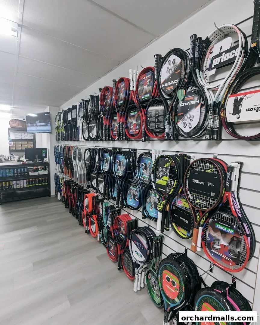 A wide selection of tennis rackets displayed on a wall in a sports store.