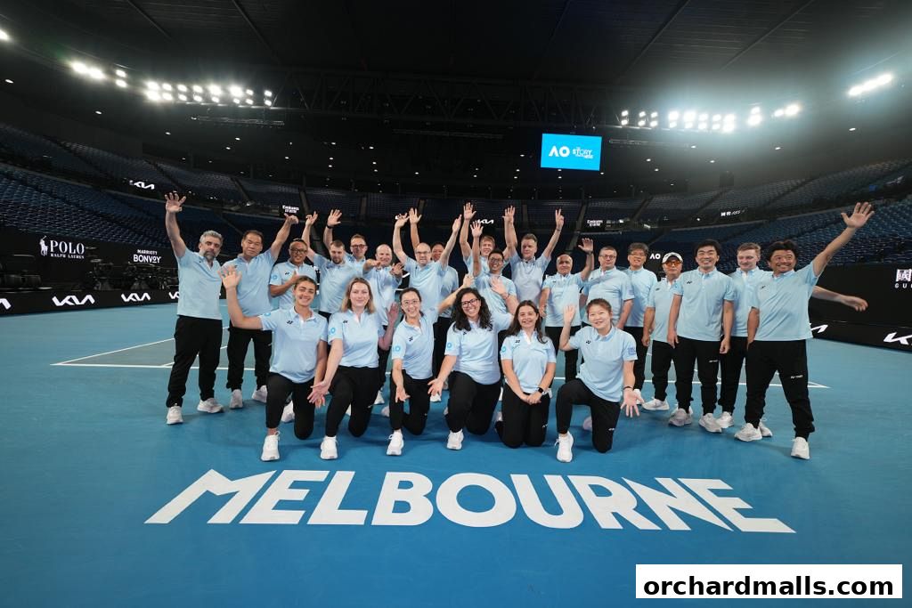 A large group of people in light blue shirts and black pants wave on a tennis court.