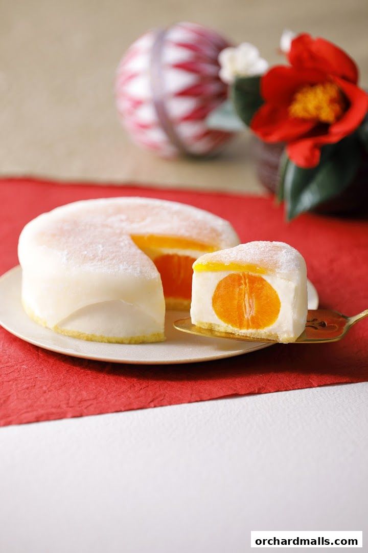 A slice of creamy cake with a whole orange inside, presented on a plate with festive decorations.