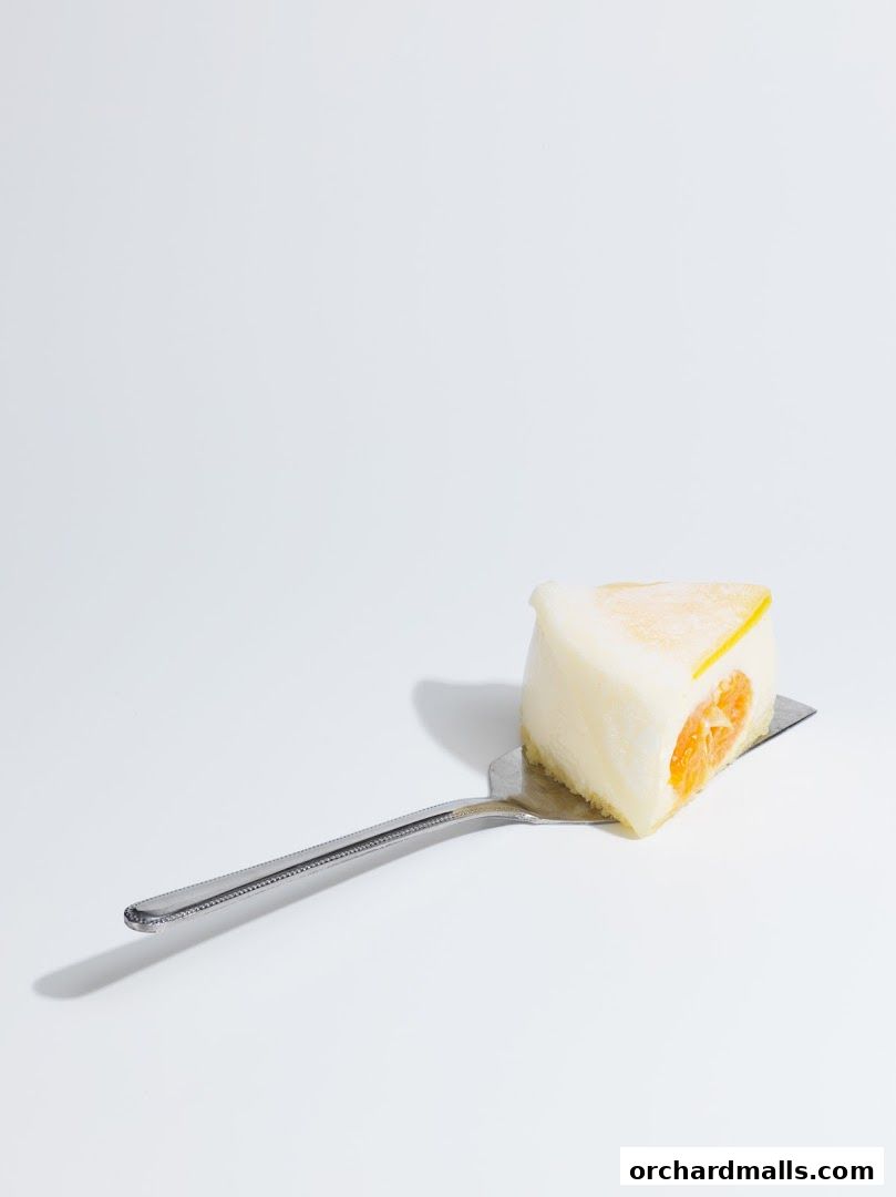 A slice of white cake with an orange filling on a cake server.