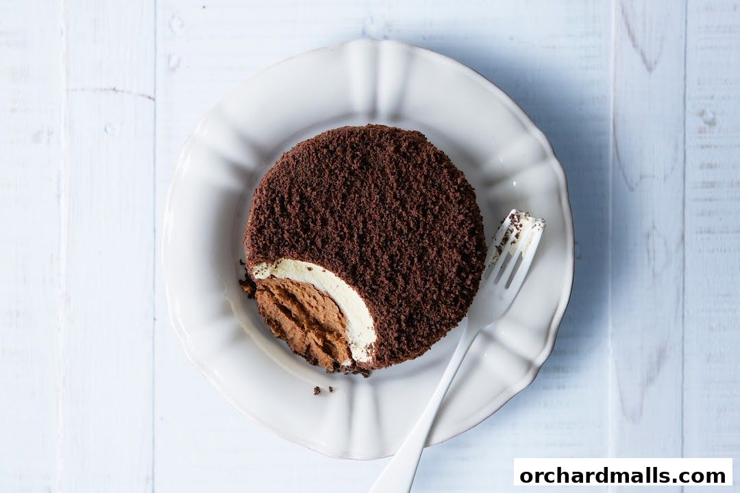 A decadent chocolate cake with layers of cream and chocolate mousse on a white plate.