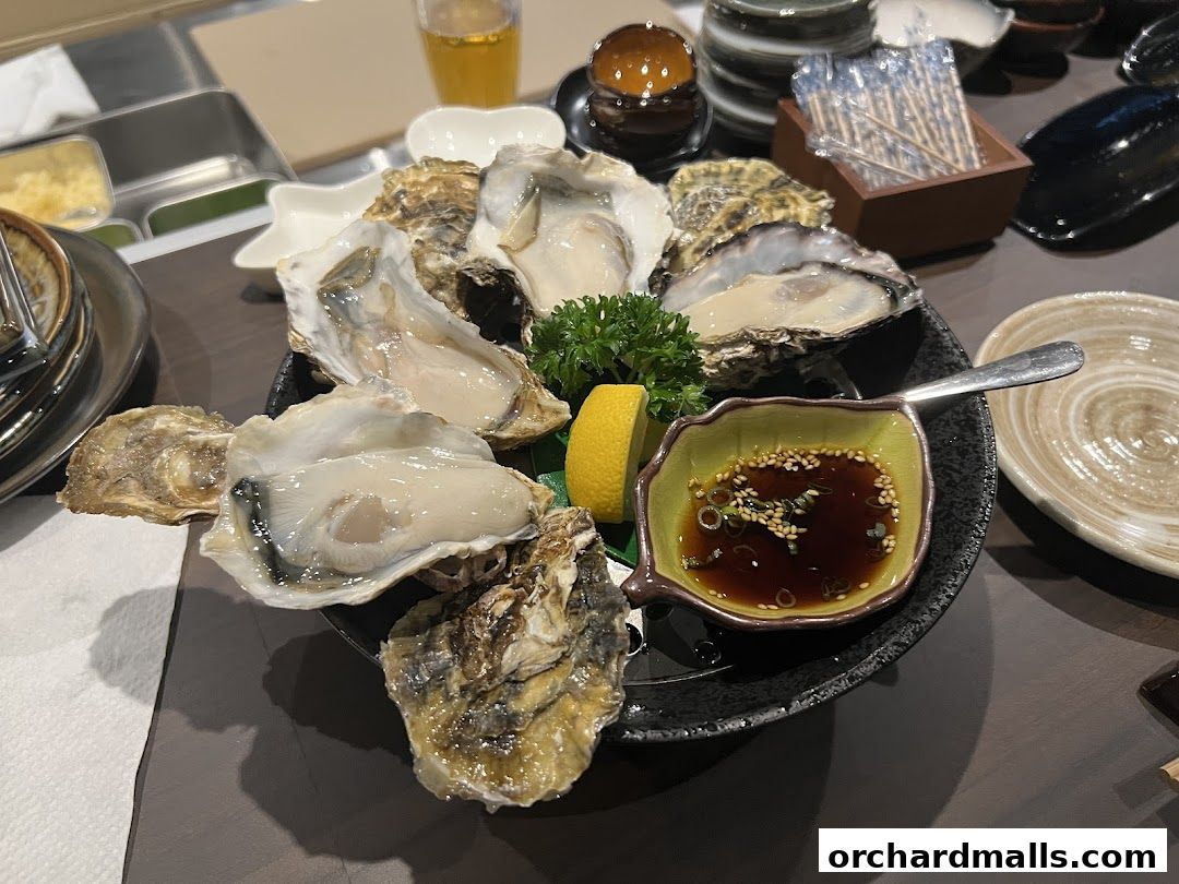 A platter of fresh oysters served with lemon and dipping sauce.