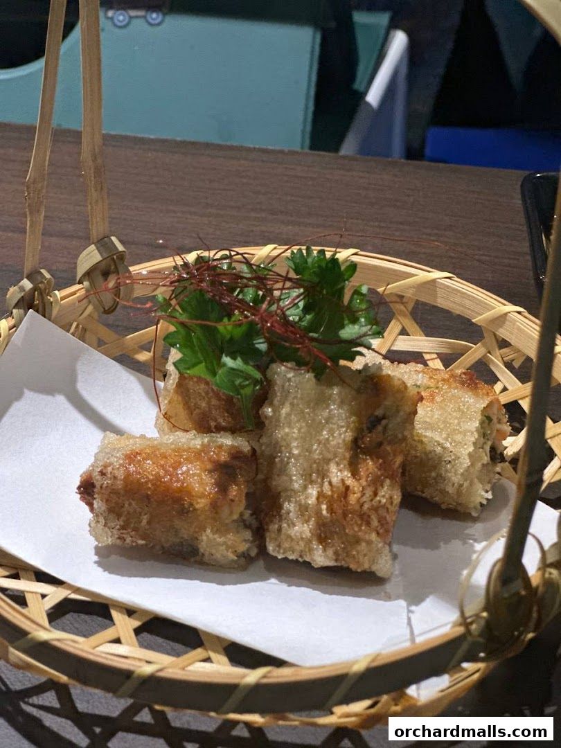 Crispy spring rolls served in a bamboo basket with garnish.