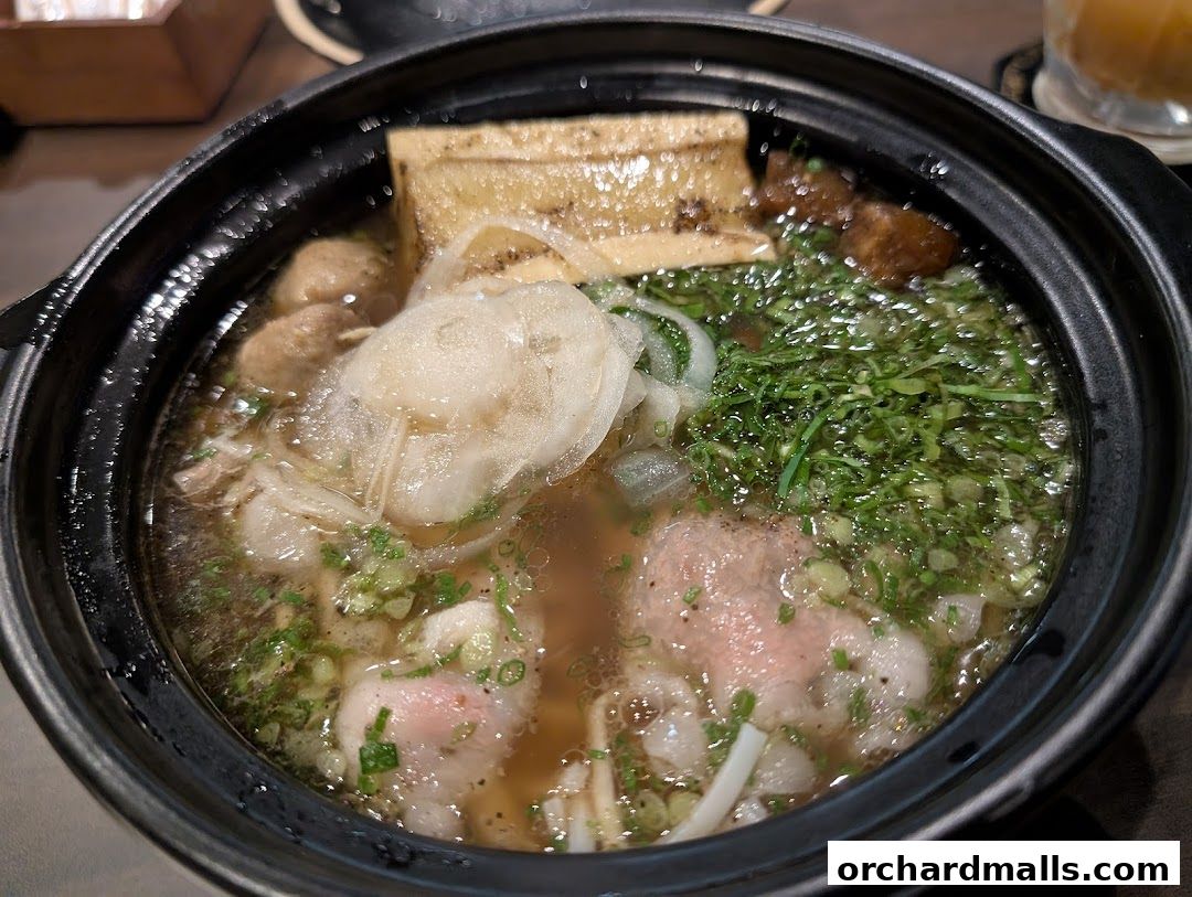 A close-up shot of a steaming bowl of Vietnamese pho with meat, noodles, and herbs.
