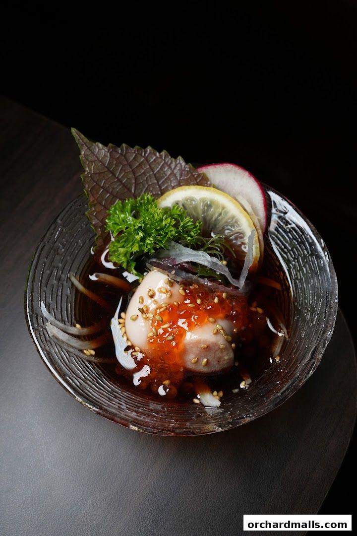 A close-up of a delicate seafood dish with garnishes in a clear bowl.