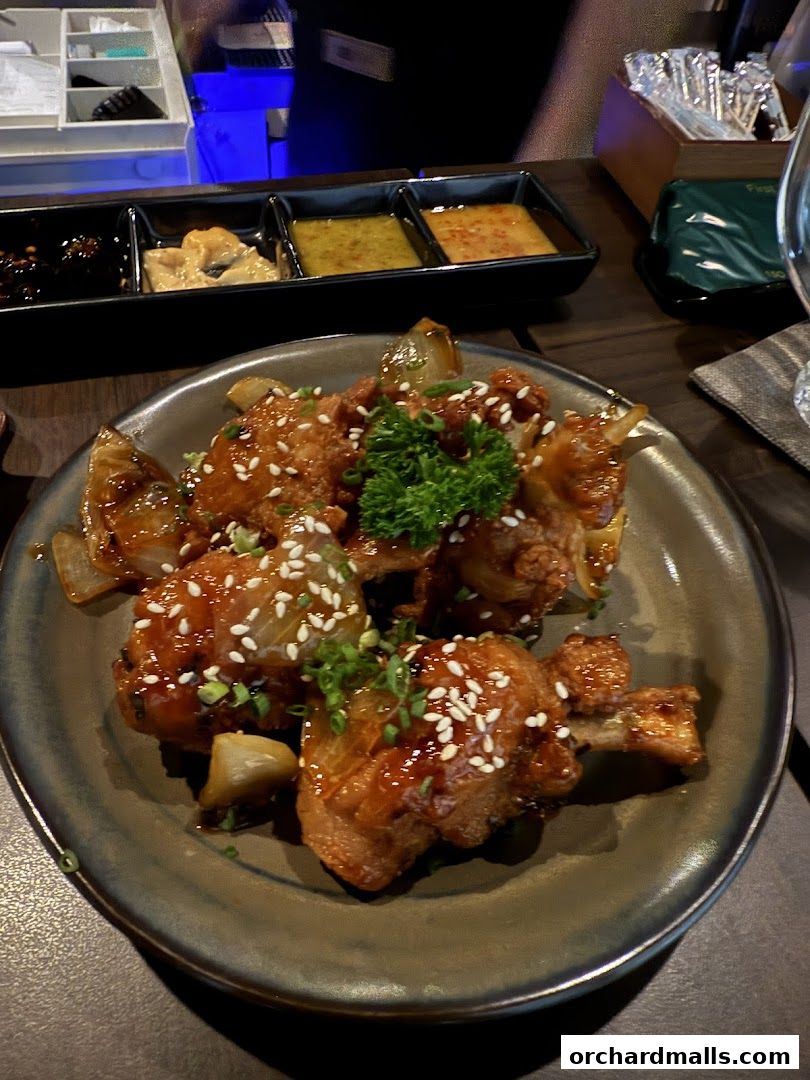 A plate of glazed chicken wings with sesame seeds and chopped green onions.