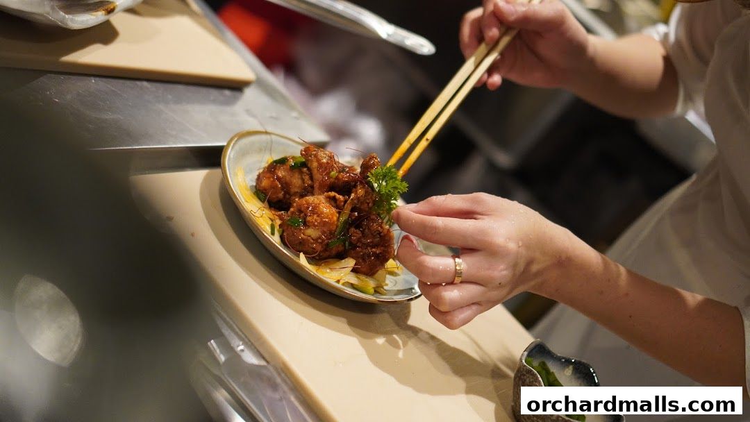 A chef garnishes a plate of fried food with chopsticks and parsley.