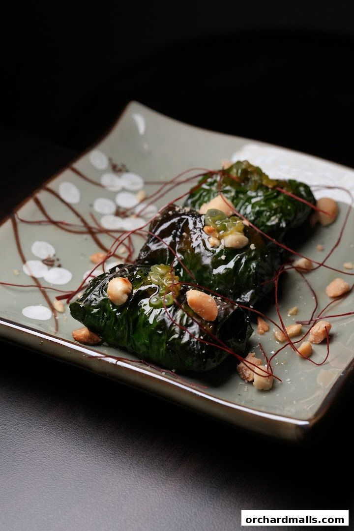 Three savory rolls topped with nuts and sauce on a decorative plate.