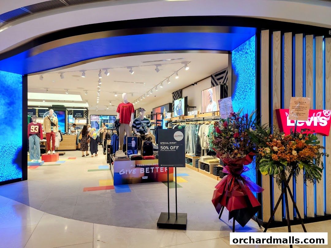 The entrance of a Levi's store with mannequins, clothing displays, and floral arrangements.