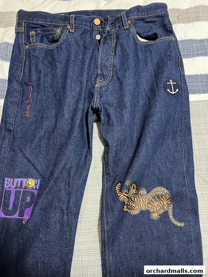 A pair of dark wash denim jeans with graphic prints and patches.