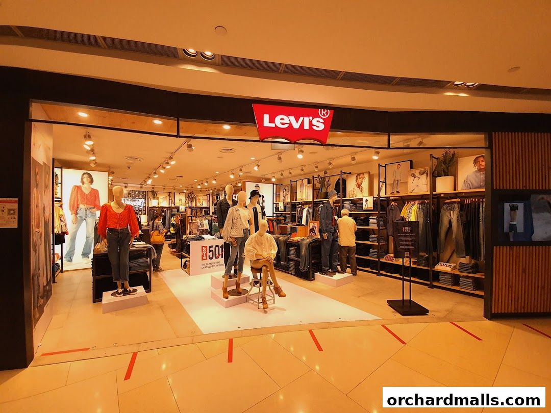 The entrance of a Levis store showcasing mannequins wearing jeans and tops, with clothing displayed on shelves and racks.