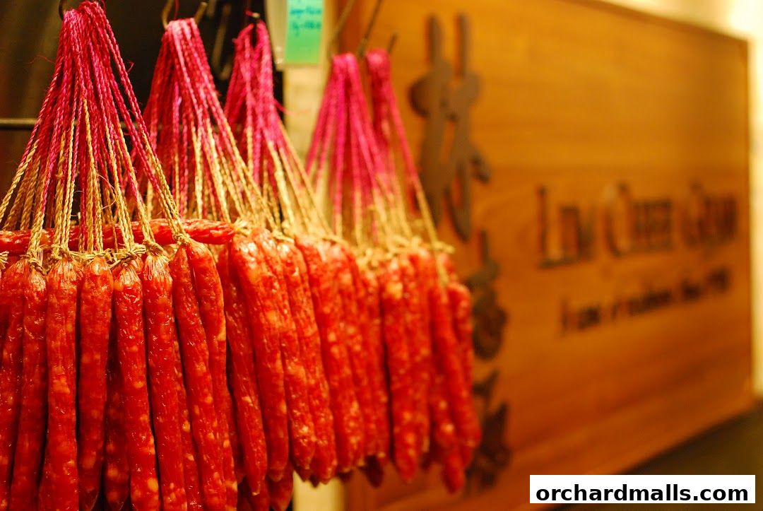 Bundles of dried sausages hang in front of a wooden sign for Lim Chee Guan.
