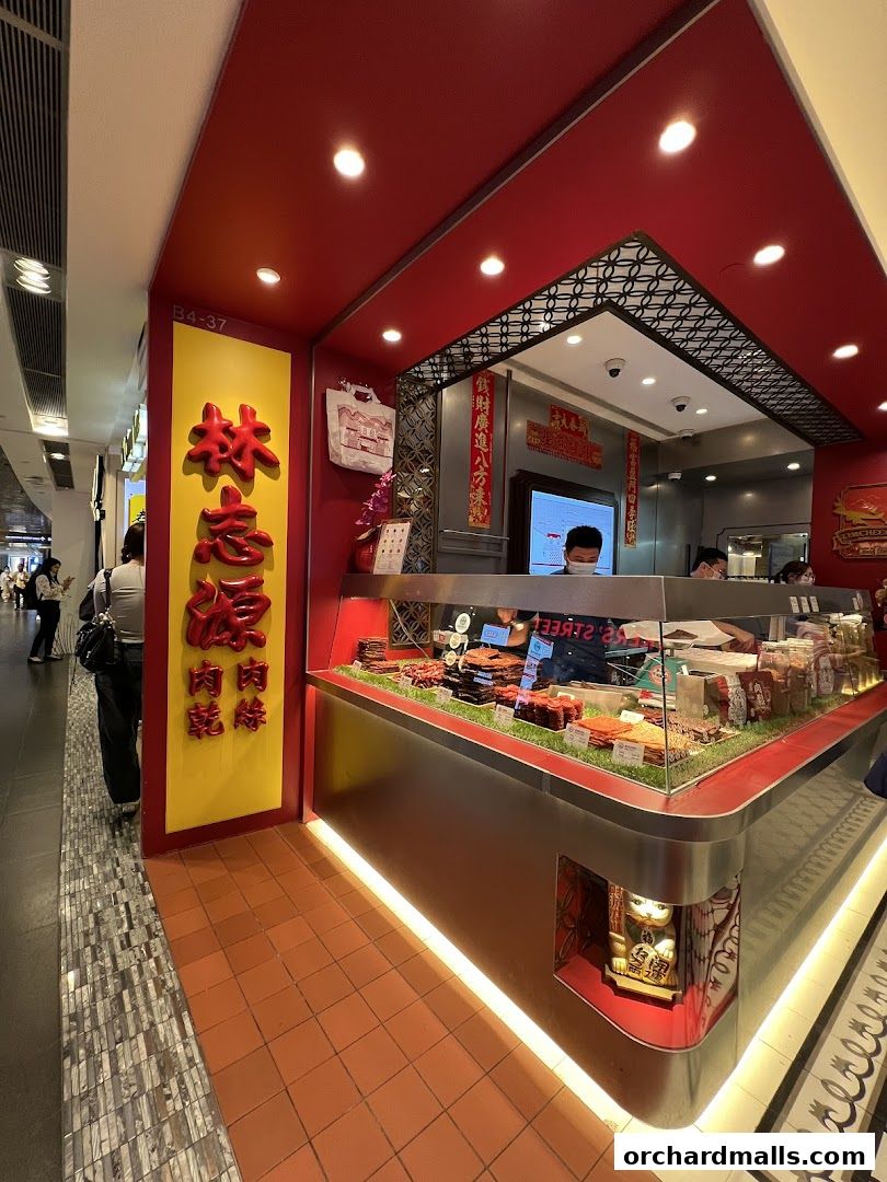 A brightly lit shop selling dried meat products with staff serving customers.