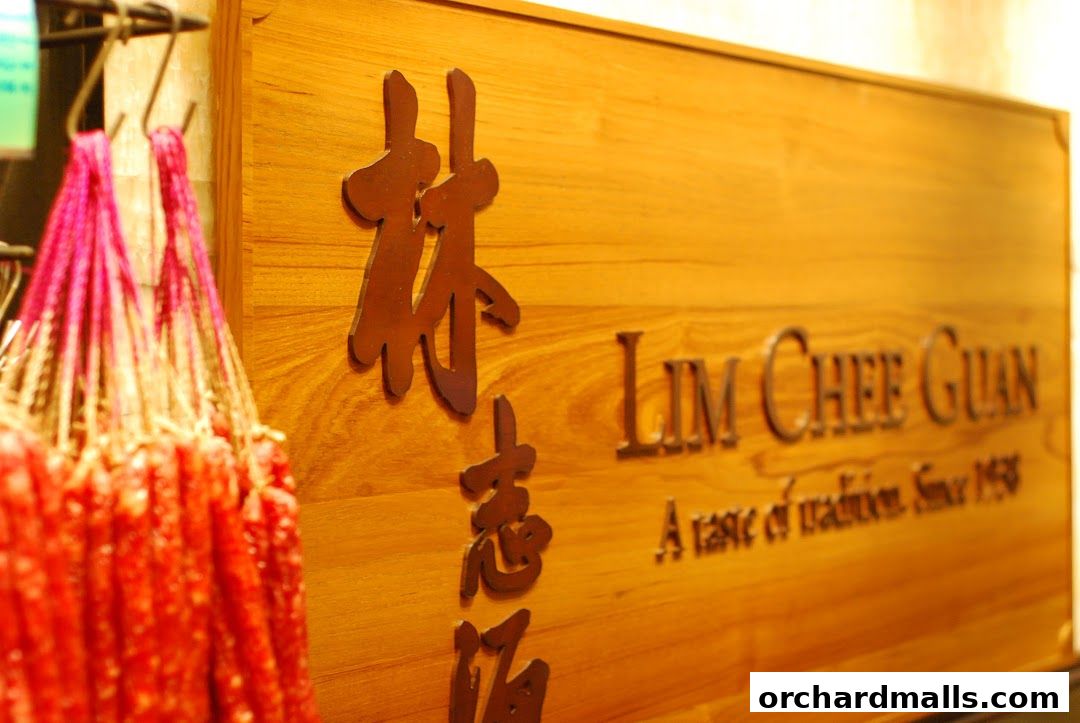 A wooden sign with embossed text 'Lim Chee Guan' and hanging strings of dried sausages.