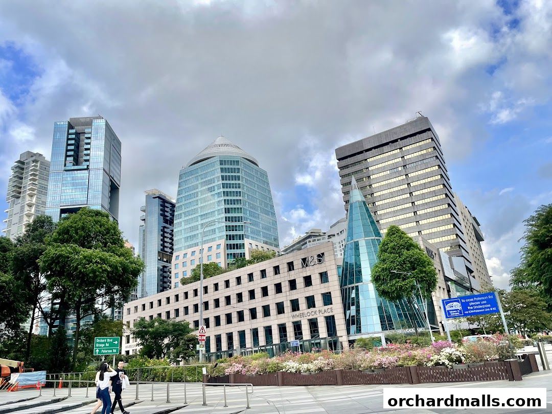 A view of modern skyscrapers and a building with a glass pyramid in a city setting.