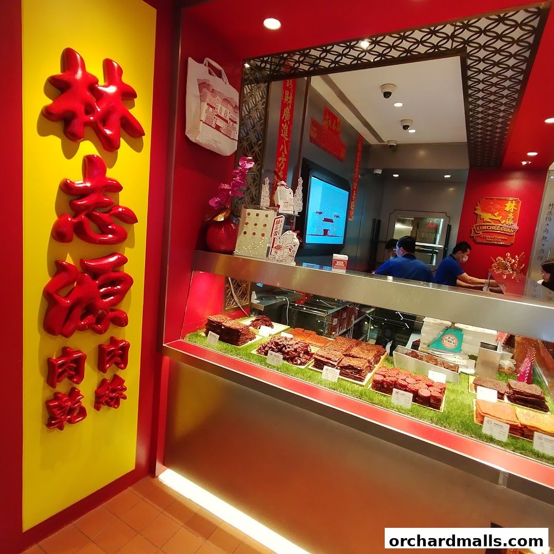 A brightly lit shop interior showcasing a display of bak kwa and other meat products.