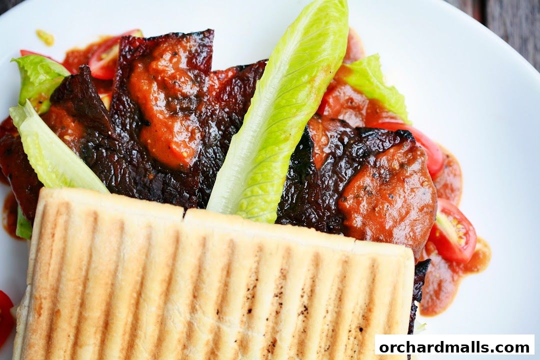 A close-up shot of a gourmet sandwich with grilled meat, lettuce, and tomatoes on a white plate.