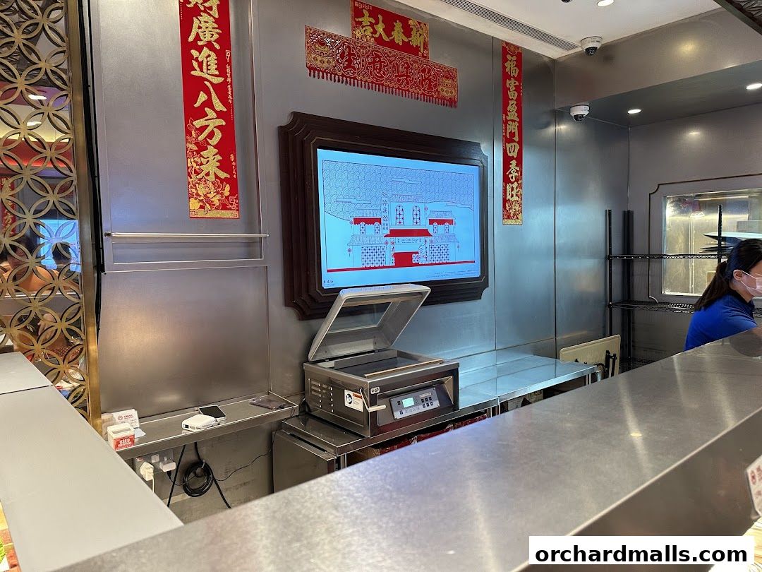 Interior view of a shop with decorative banners and a digital display showing a building.