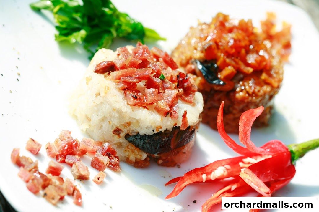 A close-up of two rice dishes, one topped with bacon bits and the other with a savory glaze, garnished with chili.