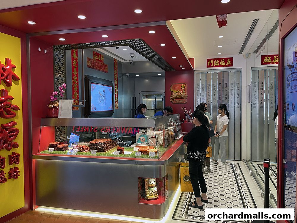 Customers queue at a Lim Chee Guan store, with a display of meat products and signage.