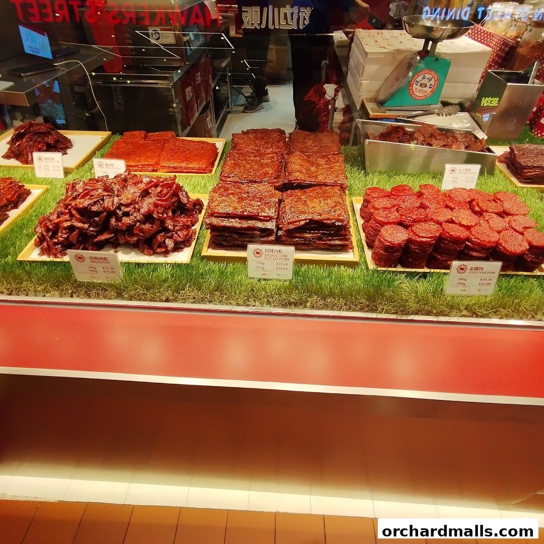 A display of various types of bak kwa (dried meat) on a grassy surface.