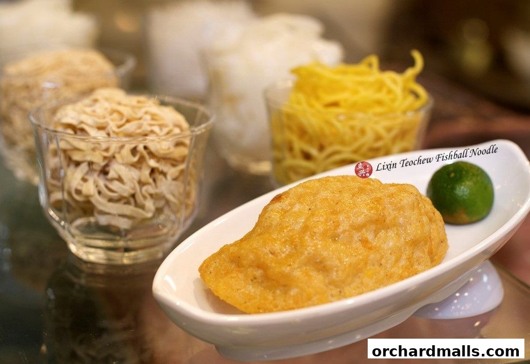 A close-up of a large fishball with noodles and a lime, presented in a dish.