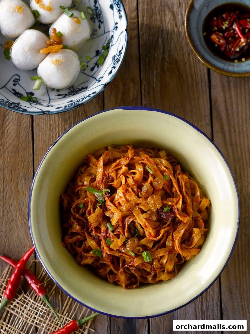 A close-up shot of delicious Teochew fishball noodles with a side of fishballs and chili.
