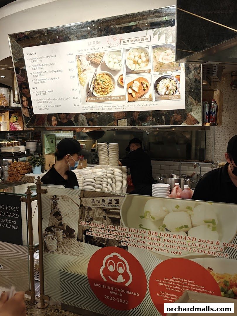 A menu board for Li Xin Teochew Fishball Noodles, showcasing various noodle and soup dishes with prices.