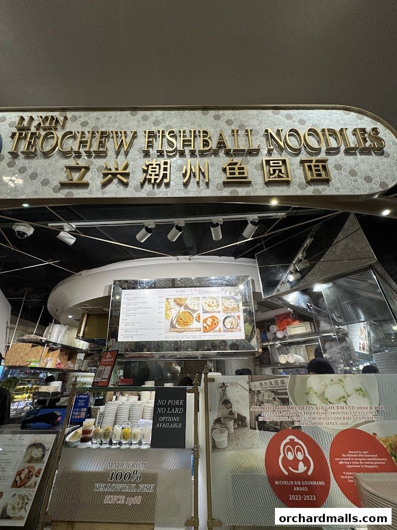The entrance of LiXin Teochew Fishball Noodles, featuring its signage and a menu display.