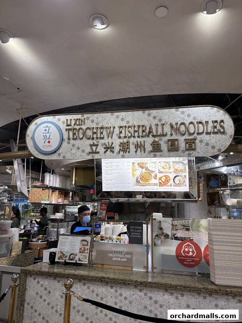 A counter at Li Xin Teochew Fishball Noodles with a menu and staff serving customers.
