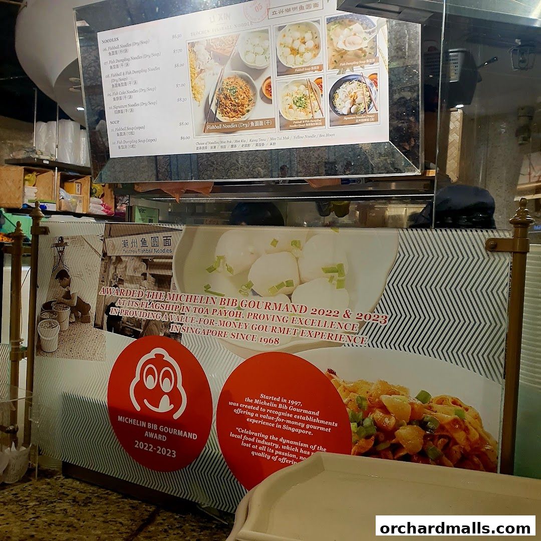 A menu board for Li Xin Teochew Fishball Noodles, highlighting Michelin Bib Gourmand awards.