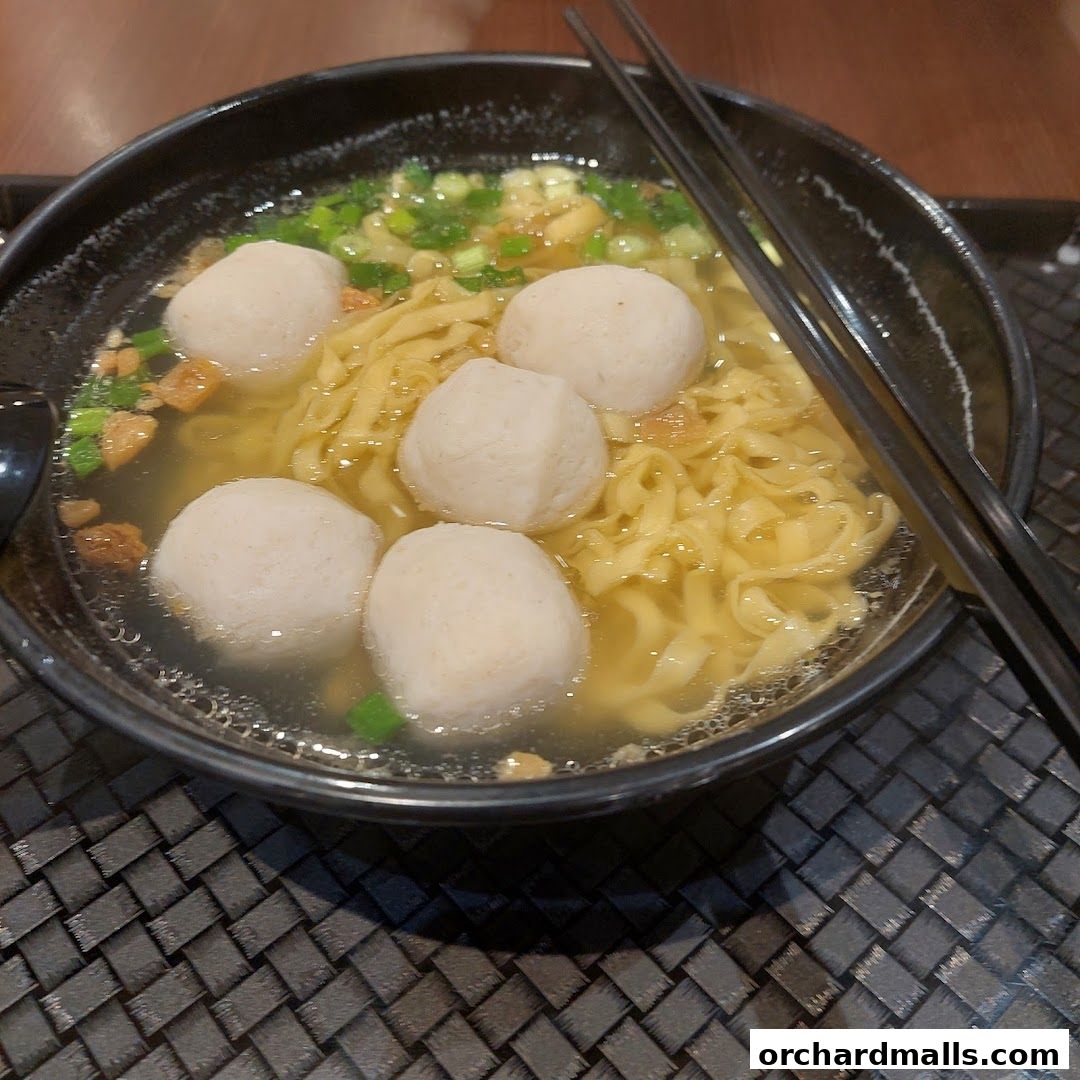 A steaming bowl of Teochew fishball noodles with chopsticks on the side.