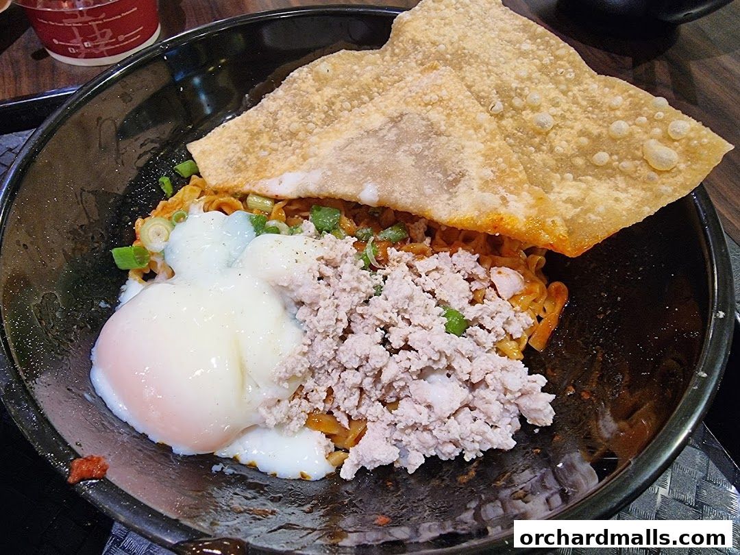A close-up of a bowl of Teochew fishball noodles with minced meat and a soft-boiled egg.
