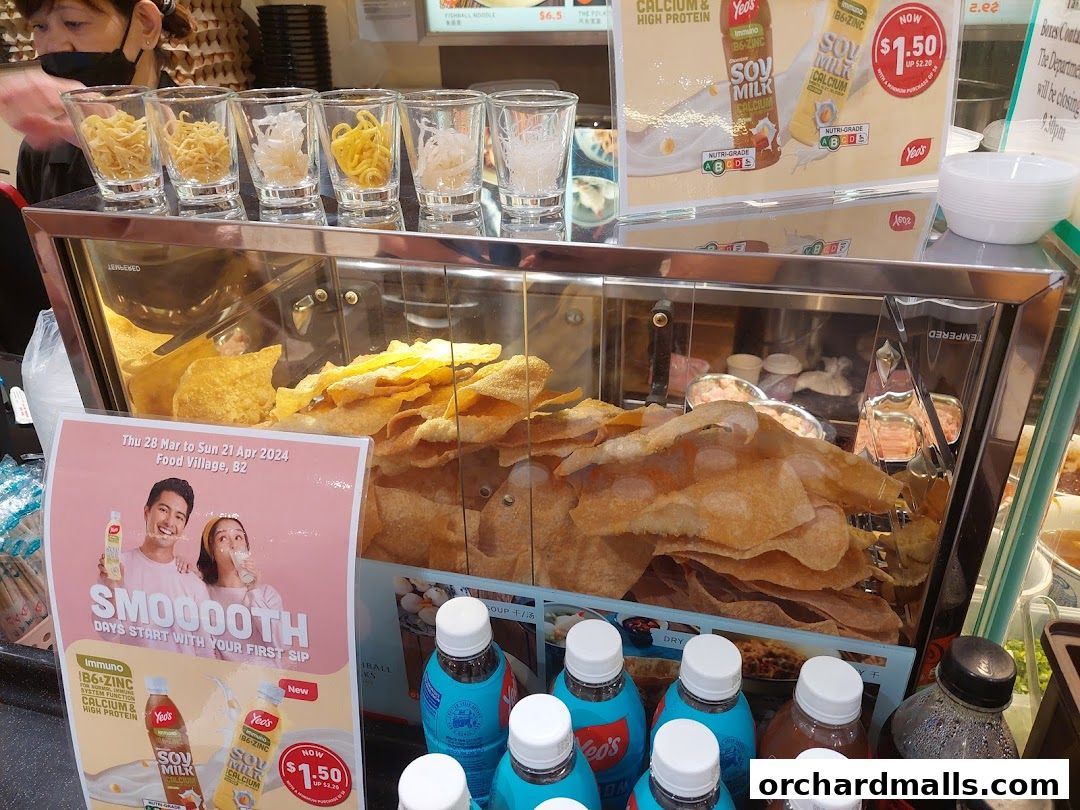A display of fried snacks and drinks at a food stall, with a promotion for soy milk.